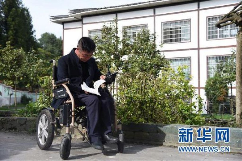 　张家嵩坐在轮椅上，拿著一本小学数学课本逐页翻看（2020年4月27日摄）