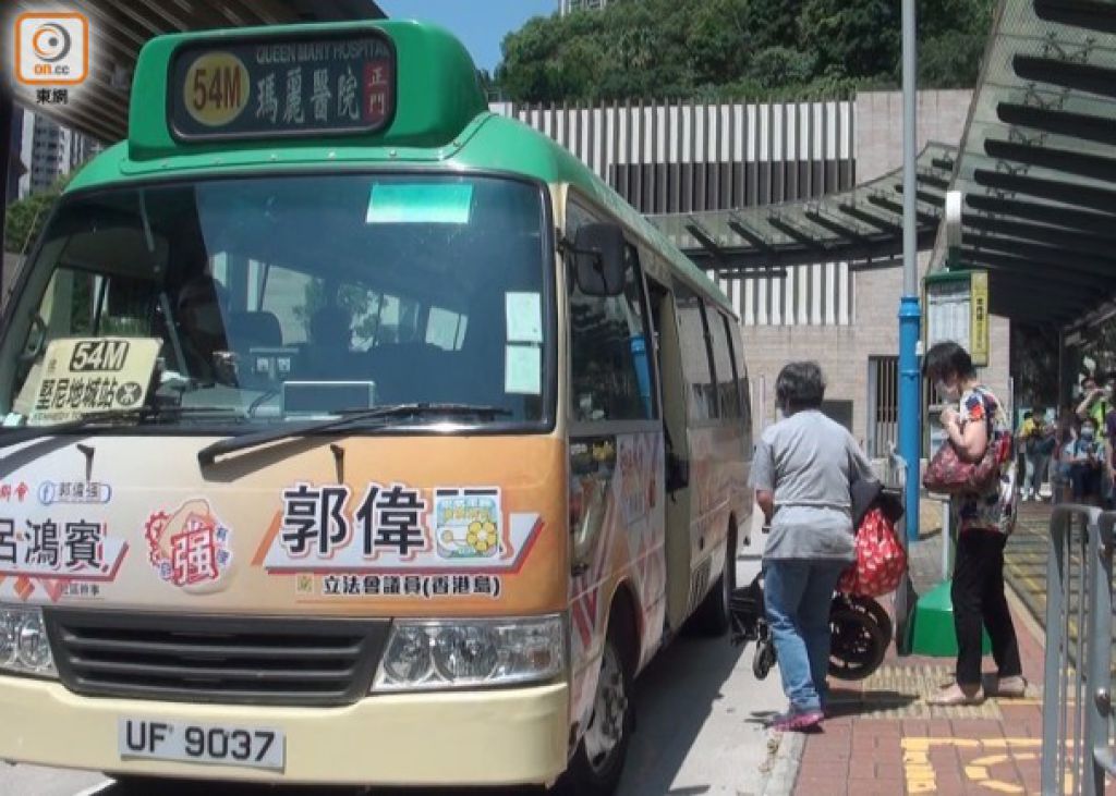 陪同轮椅人士乘车的外佣，摺好轮椅后抬上小巴。